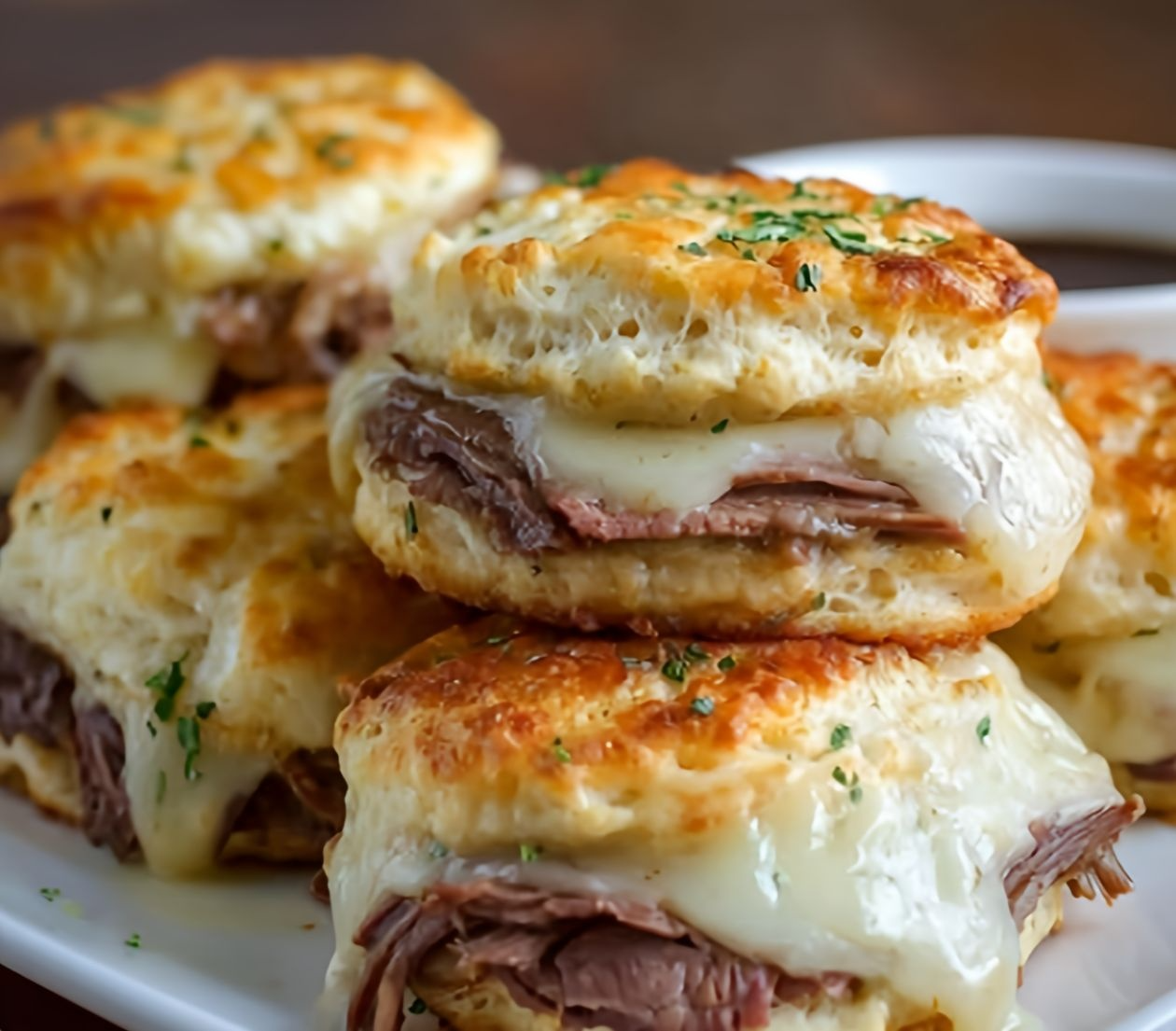 Easy baked French dip biscuits arranged on a plate, served with dipping sauce.