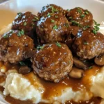 Salisbury steak meatballs in rich brown gravy served in a white slow cooker, garnished with fresh parsley